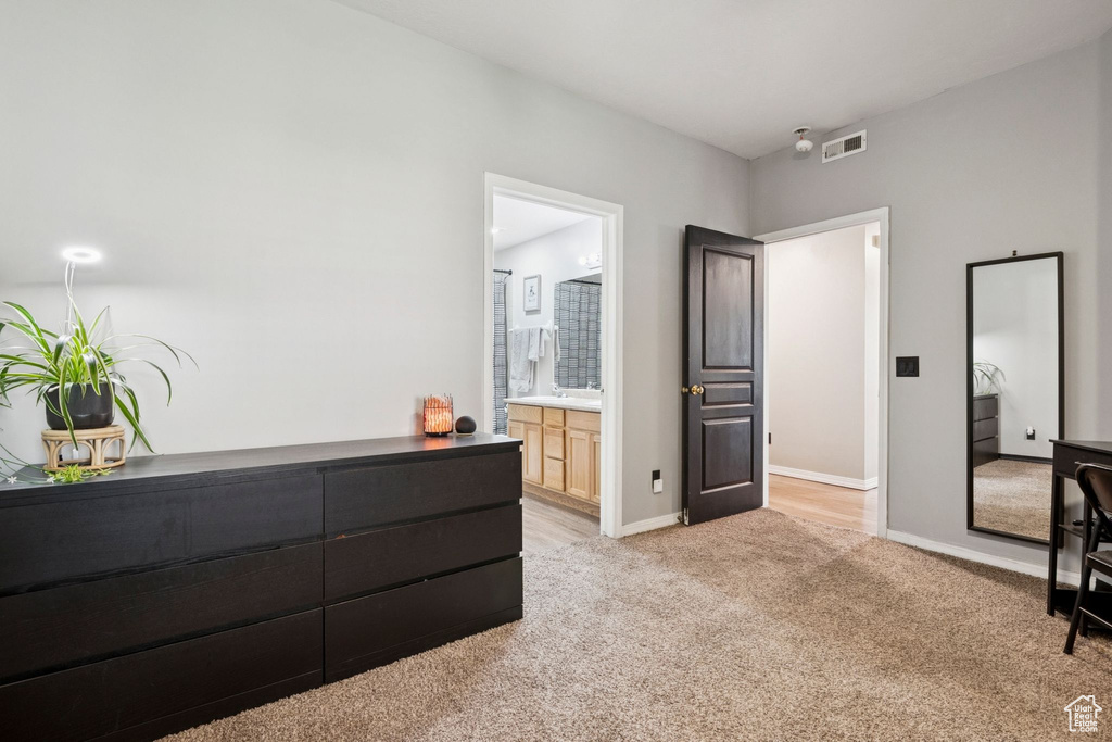 Bedroom with light carpet and connected bathroom