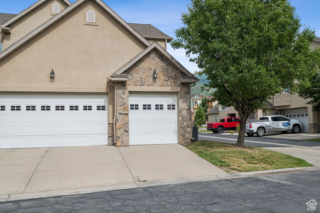 View of front facade with stone siding, stucco siding, and concrete driveway