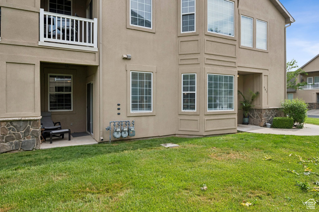 Back of property featuring stucco siding, a yard, and a balcony