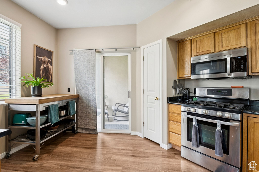 Kitchen with stainless steel appliances, light wood finished floors, brown cabinetry, and recessed lighting