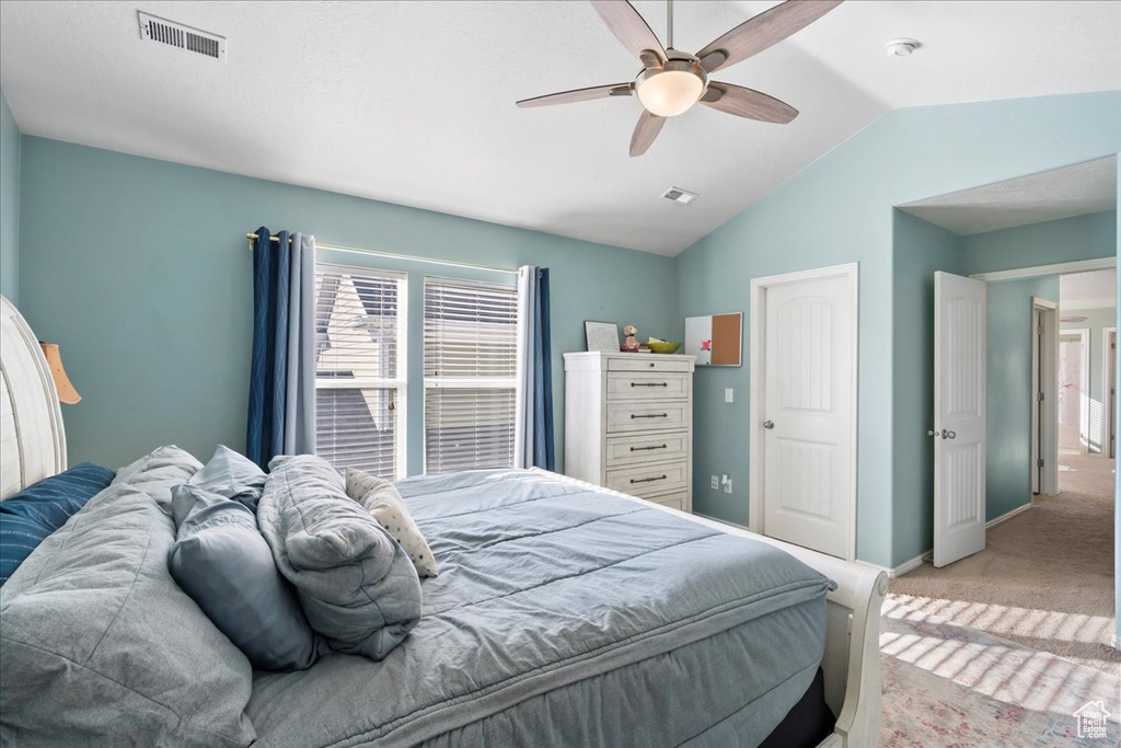 Bedroom with vaulted ceiling, light carpet, and a ceiling fan