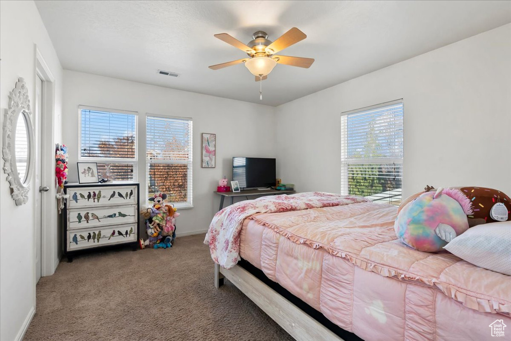Carpeted bedroom featuring multiple windows and a ceiling fan