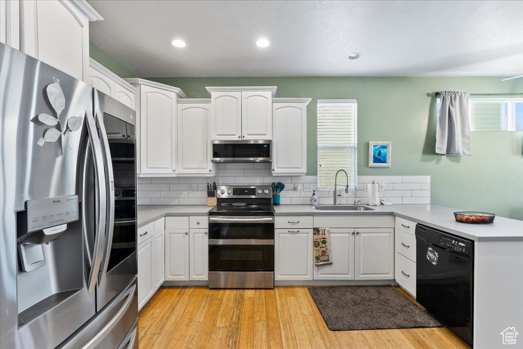 Kitchen with stainless steel appliances, plenty of natural light, a peninsula, white cabinets, and recessed lighting