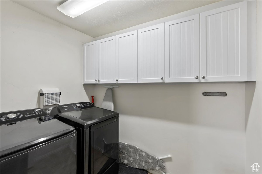 Washroom featuring cabinet space and washing machine and dryer