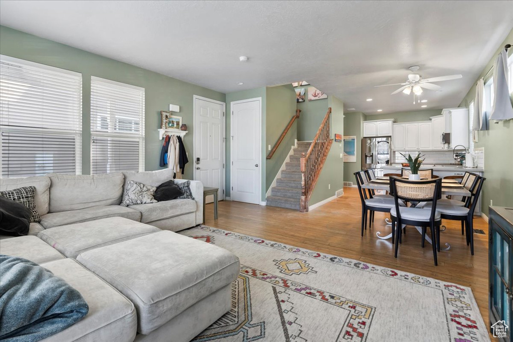 Living area featuring stairway, light wood-type flooring, a ceiling fan, and recessed lighting