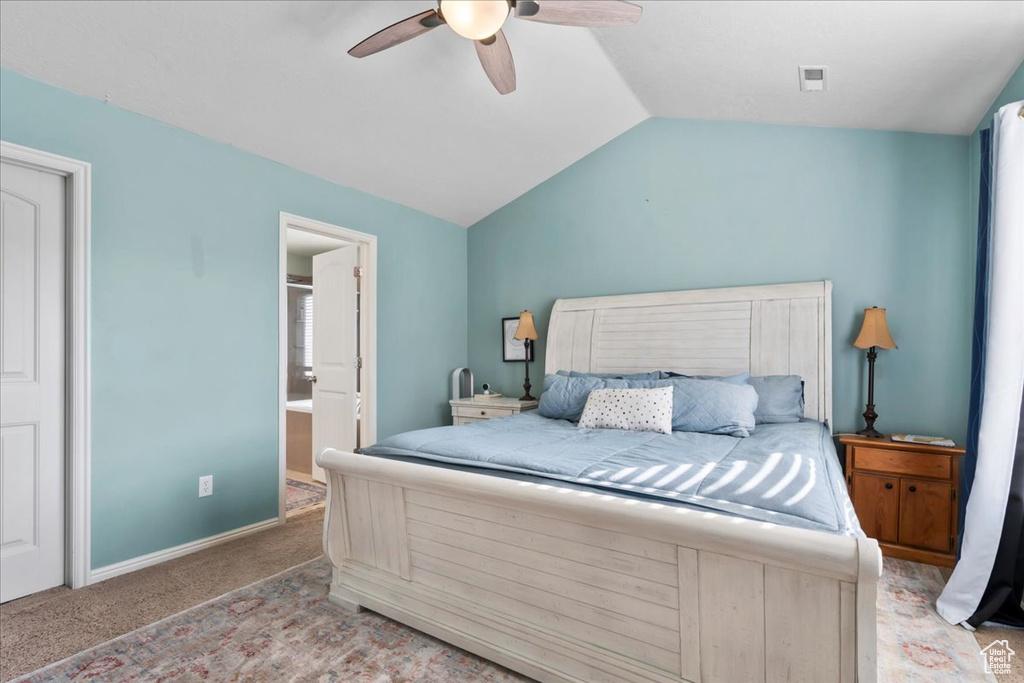 Carpeted bedroom with lofted ceiling, ceiling fan, and ensuite bath