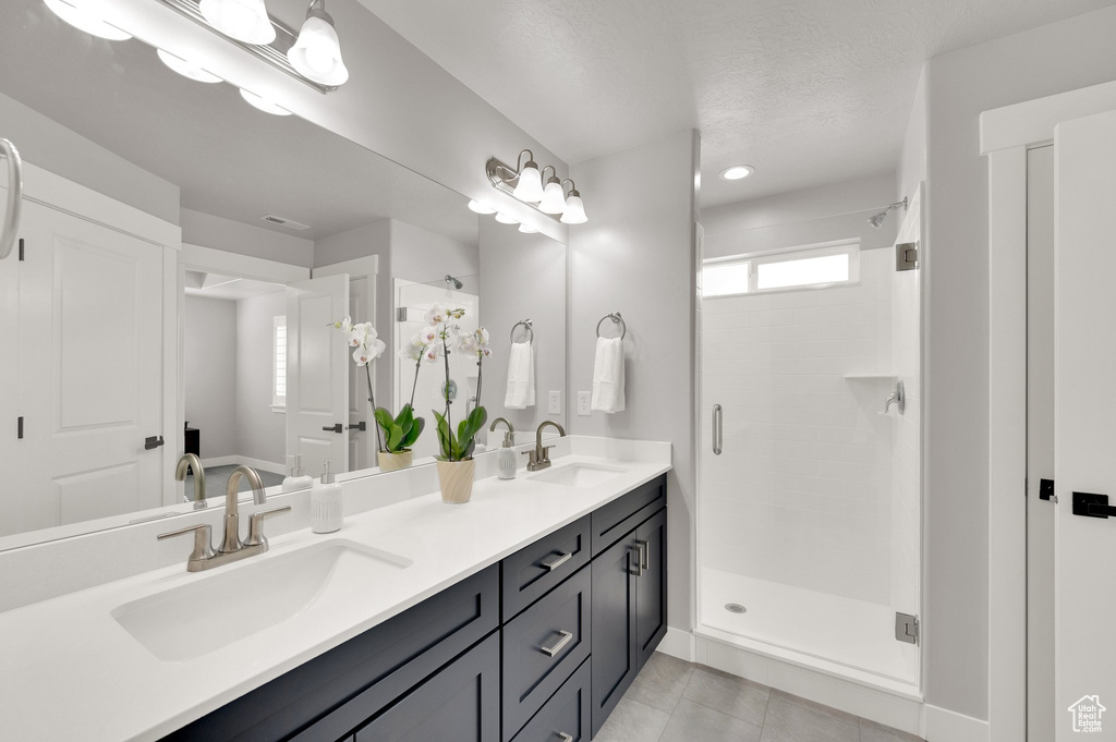 Full bathroom featuring double vanity, a stall shower, and tile patterned floors