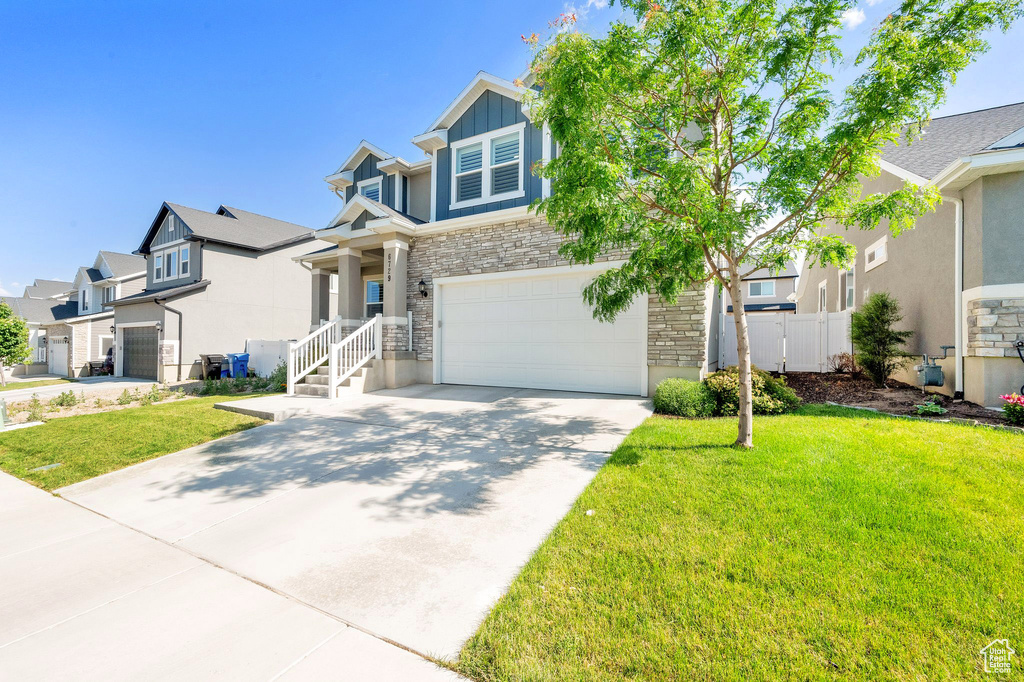 View of front of home with stone siding, driveway, an attached garage, a residential view, and stucco siding