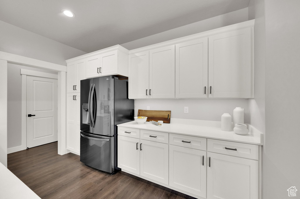 Kitchen featuring stainless steel fridge with ice dispenser, white cabinetry, light countertops, recessed lighting, and dark wood finished floors