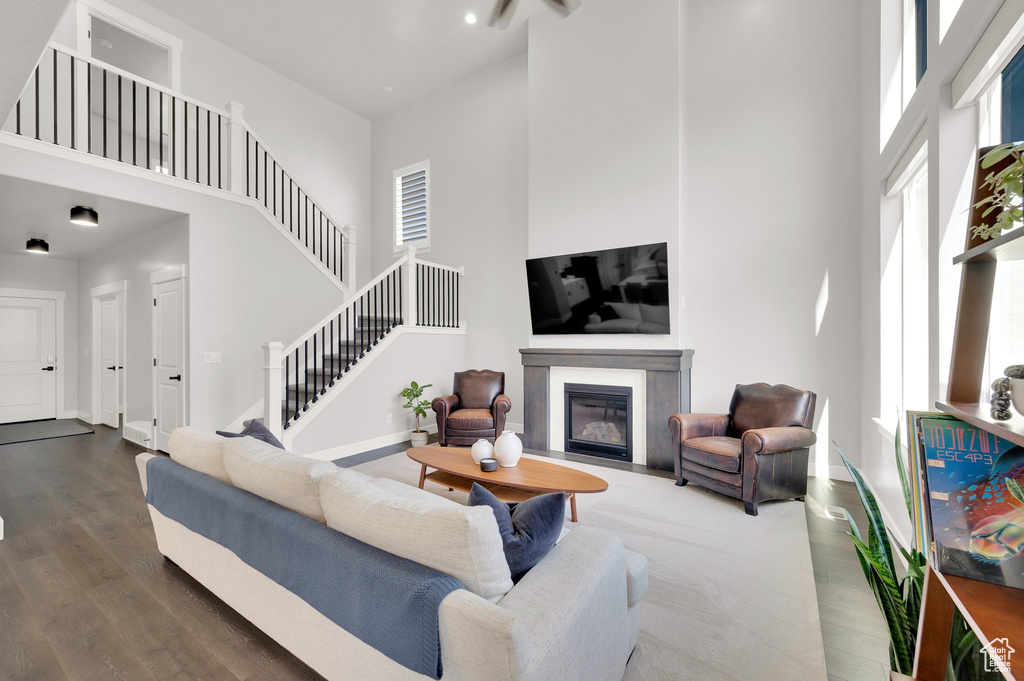 Living room with a towering ceiling, wood finished floors, a premium fireplace, and stairs