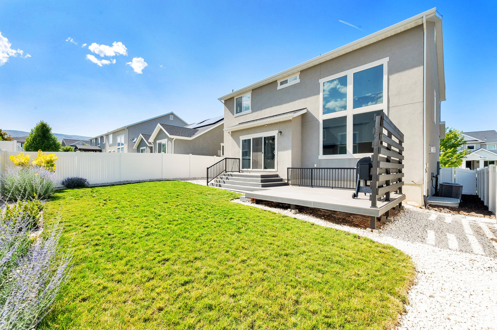 Rear view of property with stucco siding, a fenced backyard, and a wooden deck