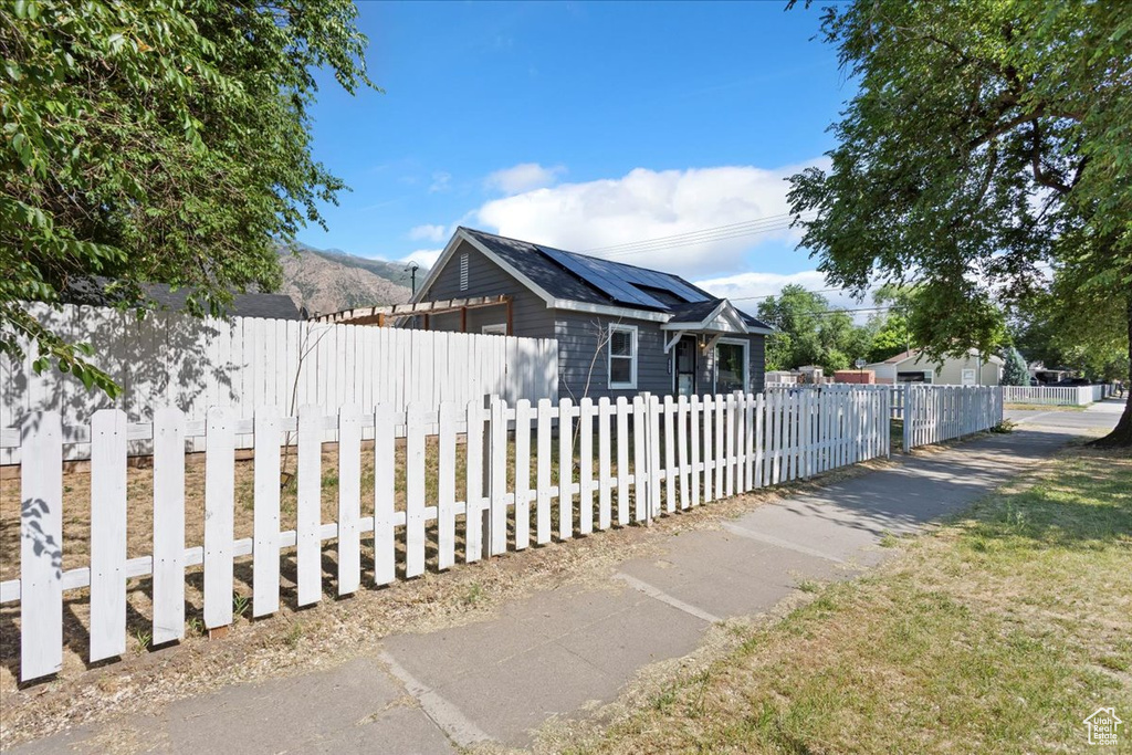 View of side of home featuring roof mounted solar panels and a fenced front yard