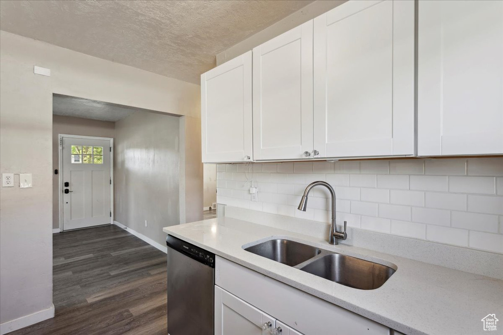 Kitchen with stainless steel dishwasher, white cabinets, dark wood-style floors, decorative backsplash, and a textured ceiling