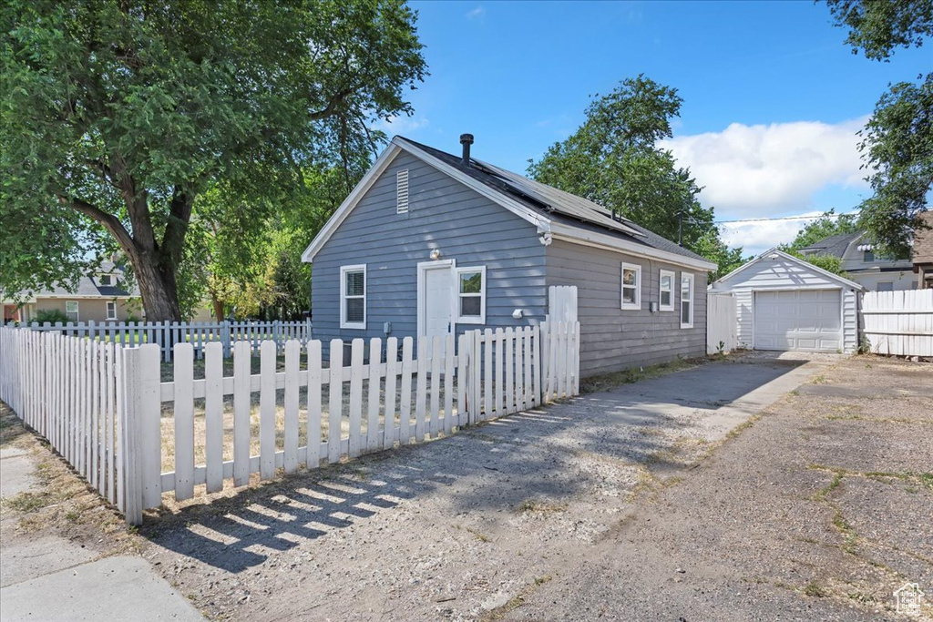 View of home's exterior with asphalt driveway, a garage, solar panels, and an outdoor structure