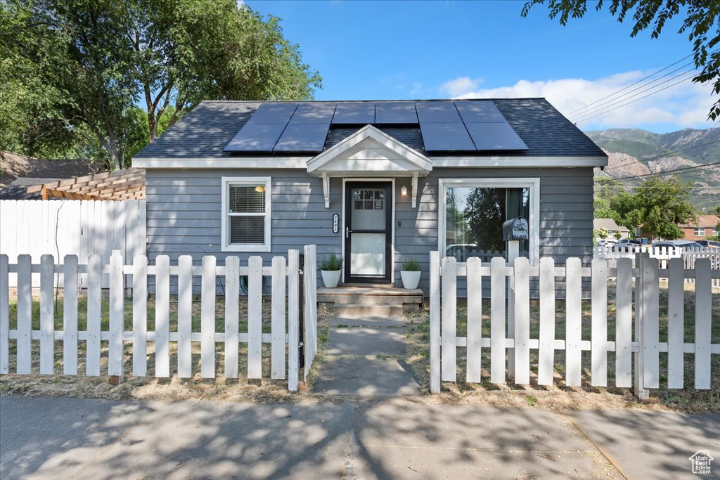 View of front of house with roof mounted solar panels, a fenced front yard, and a mountain view