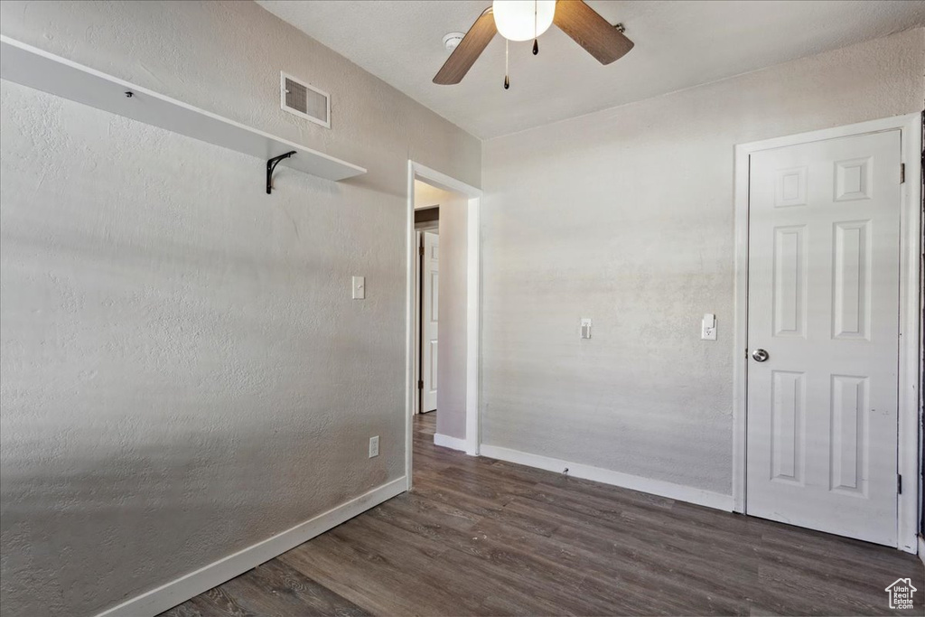 Empty room featuring dark wood-style floors and a ceiling fan