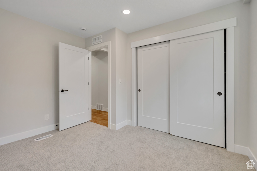 Unfurnished bedroom with carpet flooring, a closet, and recessed lighting