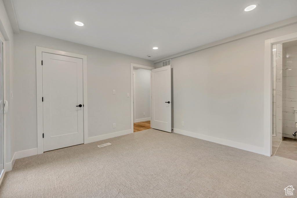 Unfurnished bedroom with light carpet, recessed lighting, and ensuite bathroom
