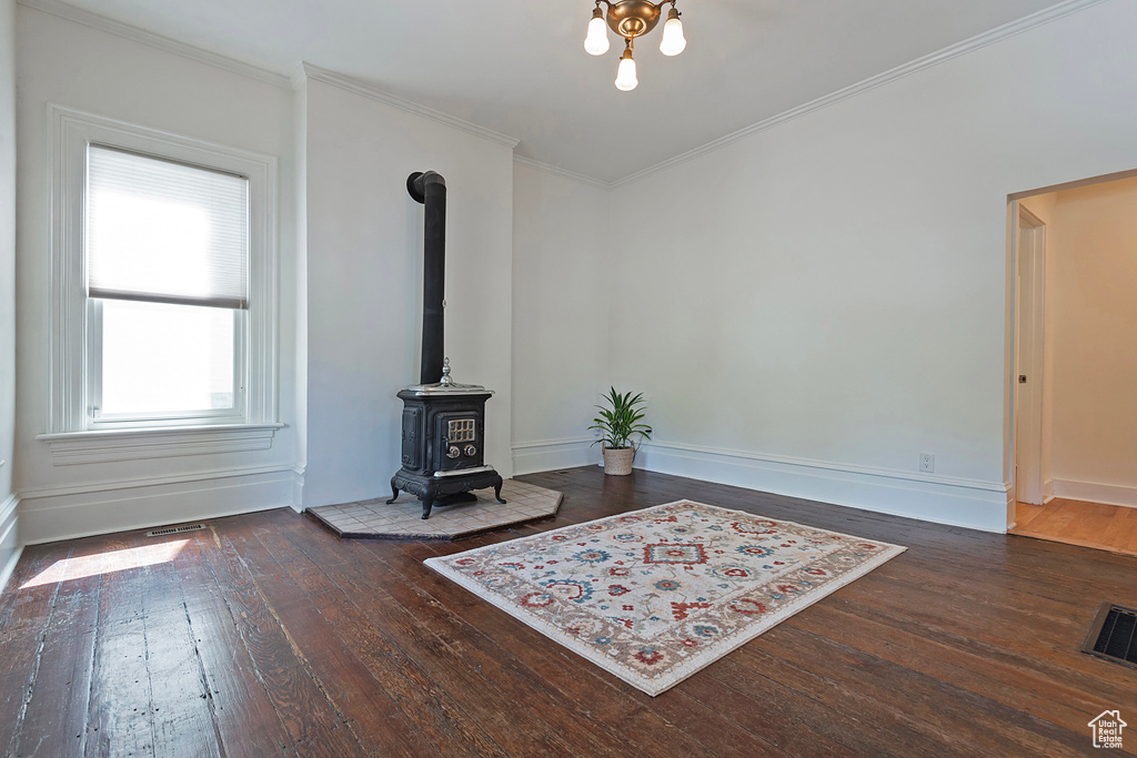 Living room with hardwood / wood-style flooring, crown molding, and a wood stove