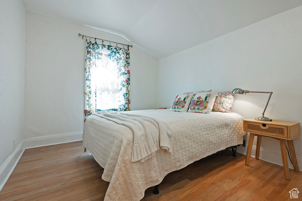 Bedroom with vaulted ceiling and light wood-style flooring