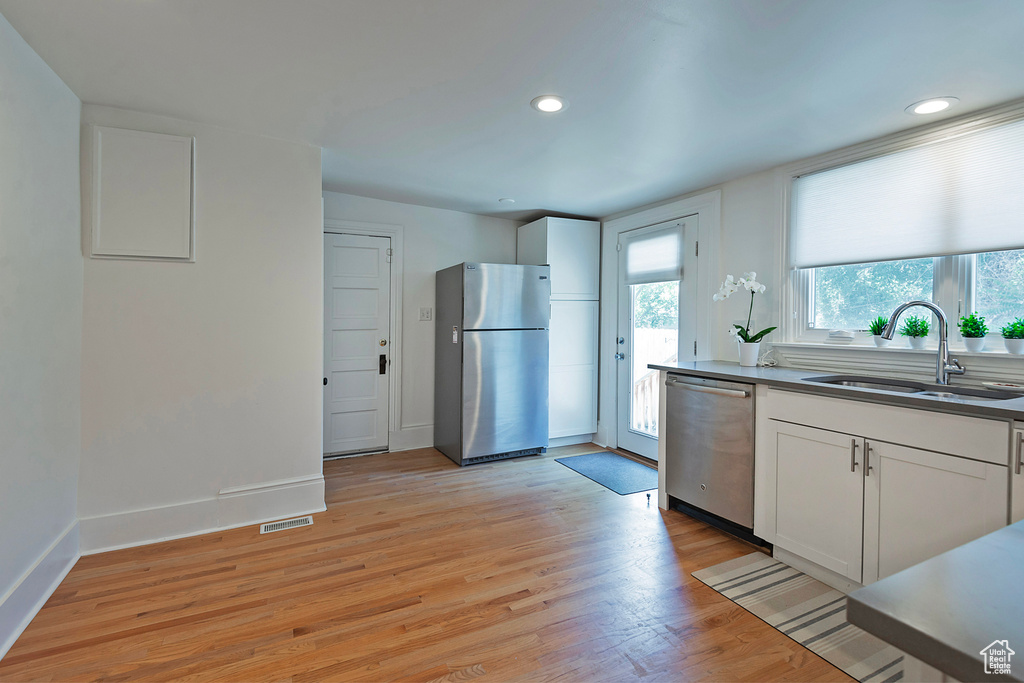 Kitchen with appliances with stainless steel finishes, light wood finished floors, white cabinetry, and recessed lighting