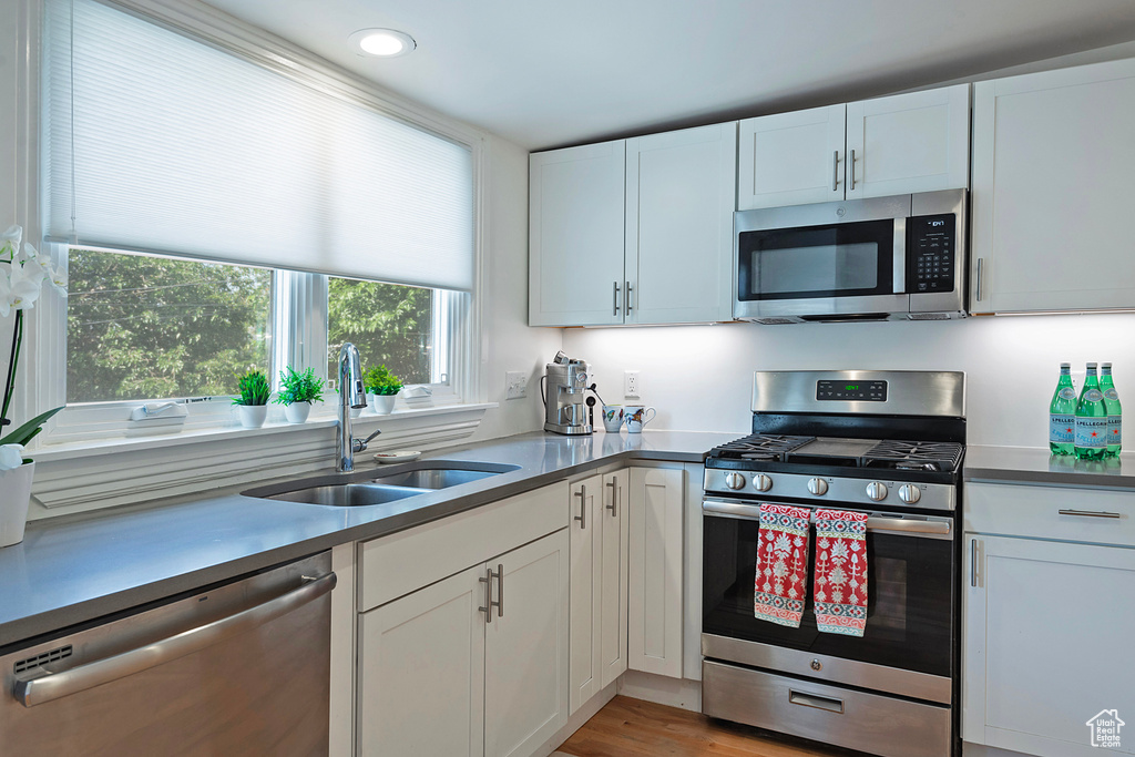 Kitchen with appliances with stainless steel finishes, white cabinetry, recessed lighting, and light wood-type flooring