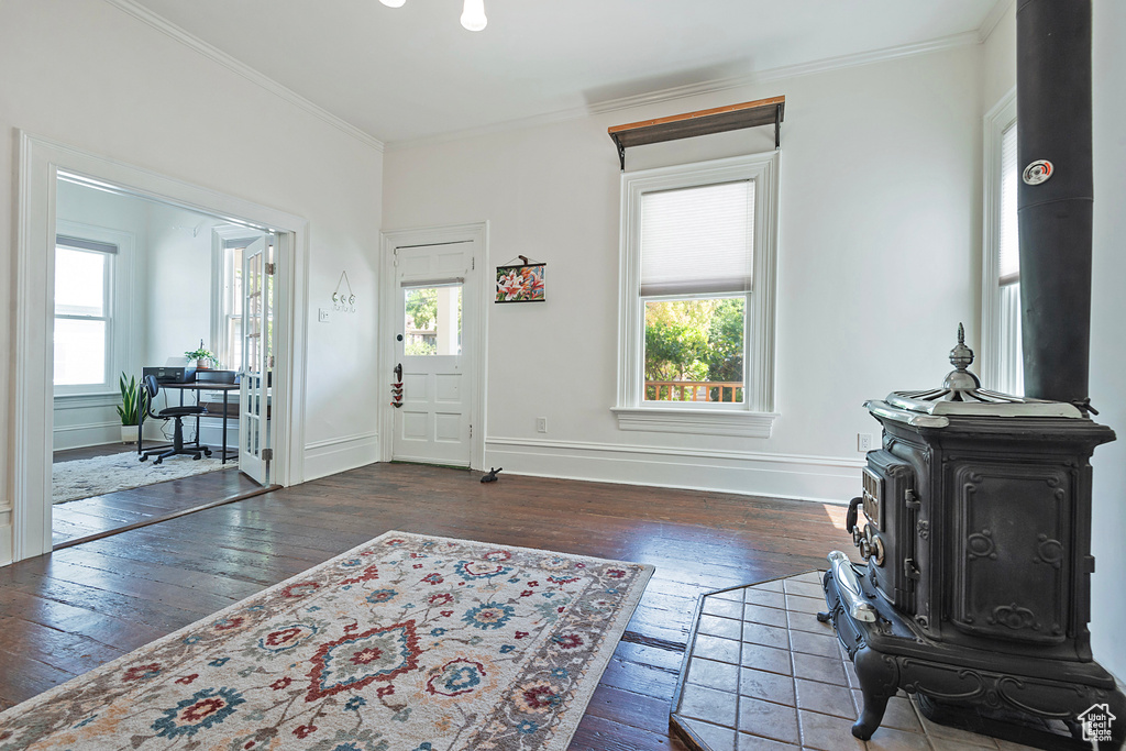 Foyer with wood-type flooring, crown molding, and a wood stove