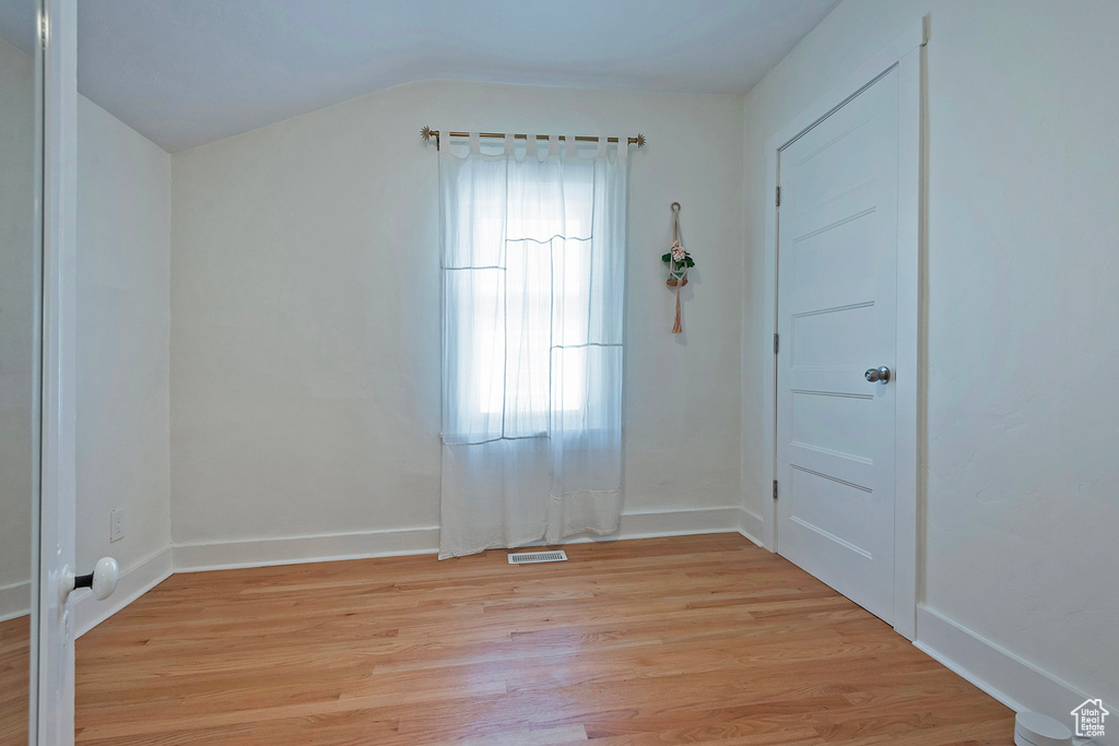 Unfurnished room with light wood-style flooring and lofted ceiling