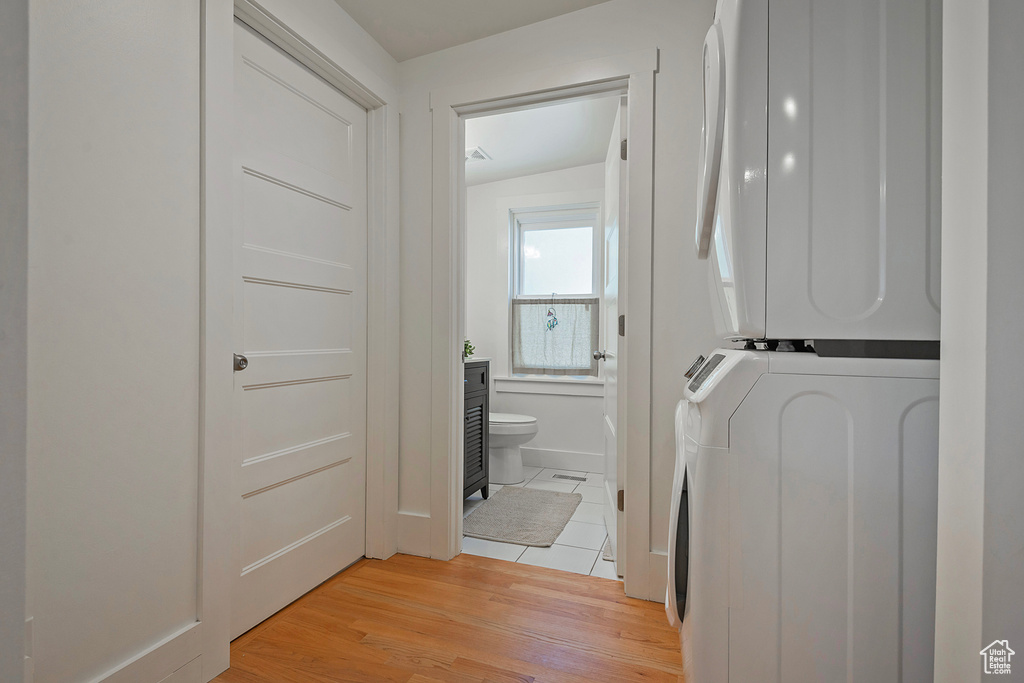 Washroom featuring estacked washer and dryer and light wood-type flooring