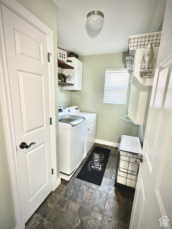 Laundry room featuring independent washer and dryer, cabinet space, and dark stone finish flooring