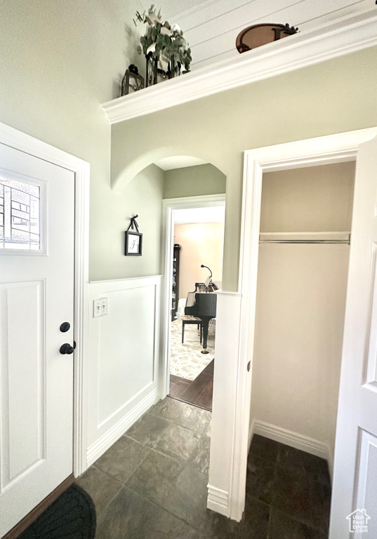Entrance foyer with wainscoting, arched walkways, and dark tile patterned floors