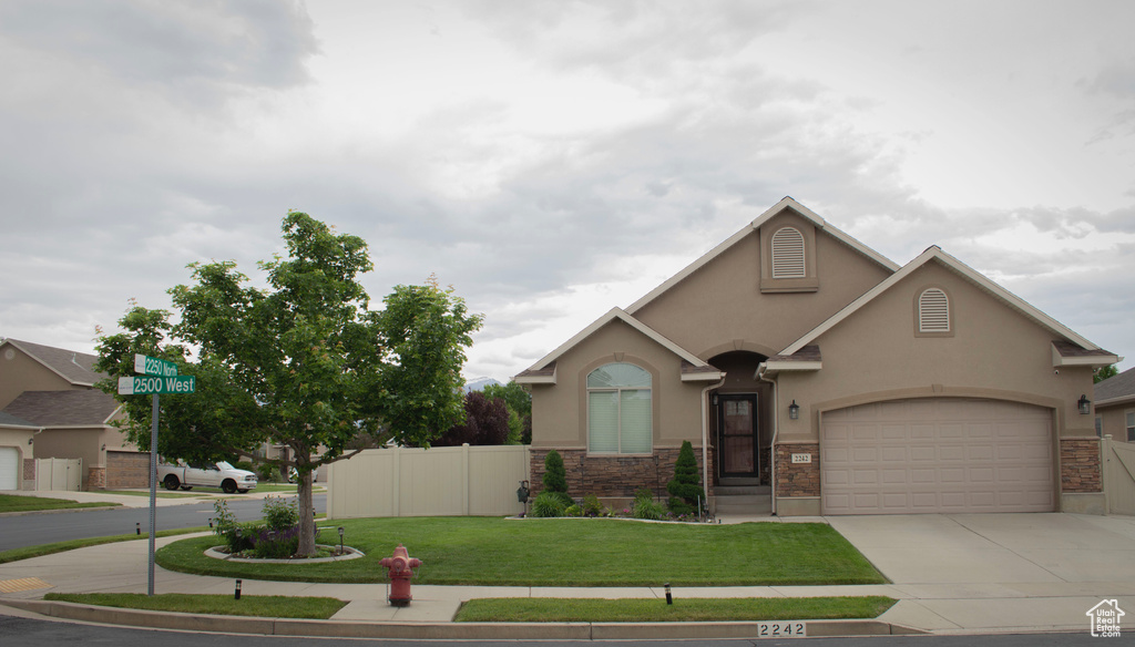View of front of property with stucco siding, concrete driveway, stone siding, and a garage