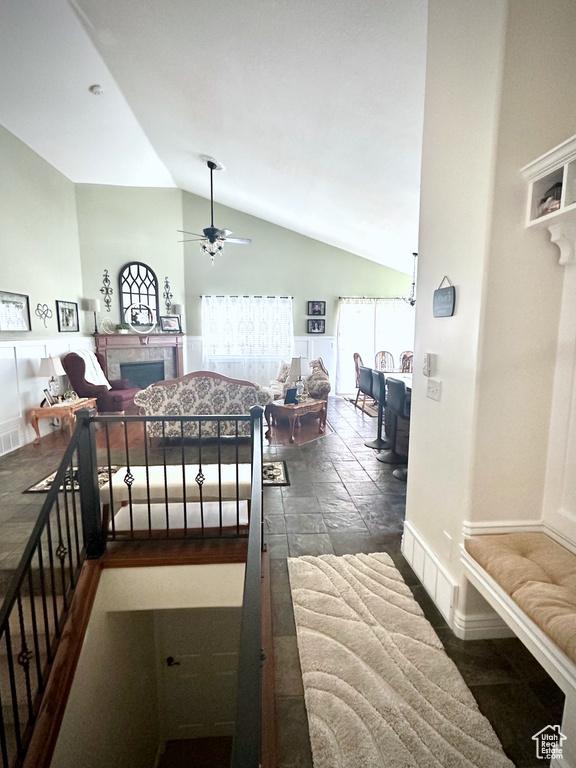 Bedroom with a fireplace, high vaulted ceiling, and stone tile flooring