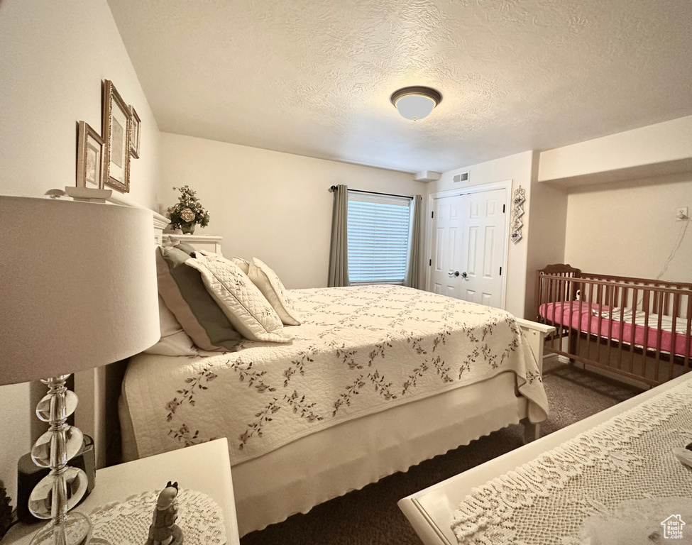 Bedroom featuring carpet, a textured ceiling, and a closet
