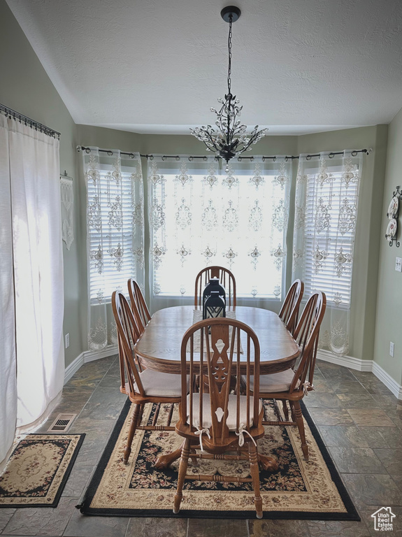 Dining room with stone tile floors, a textured ceiling, and a chandelier