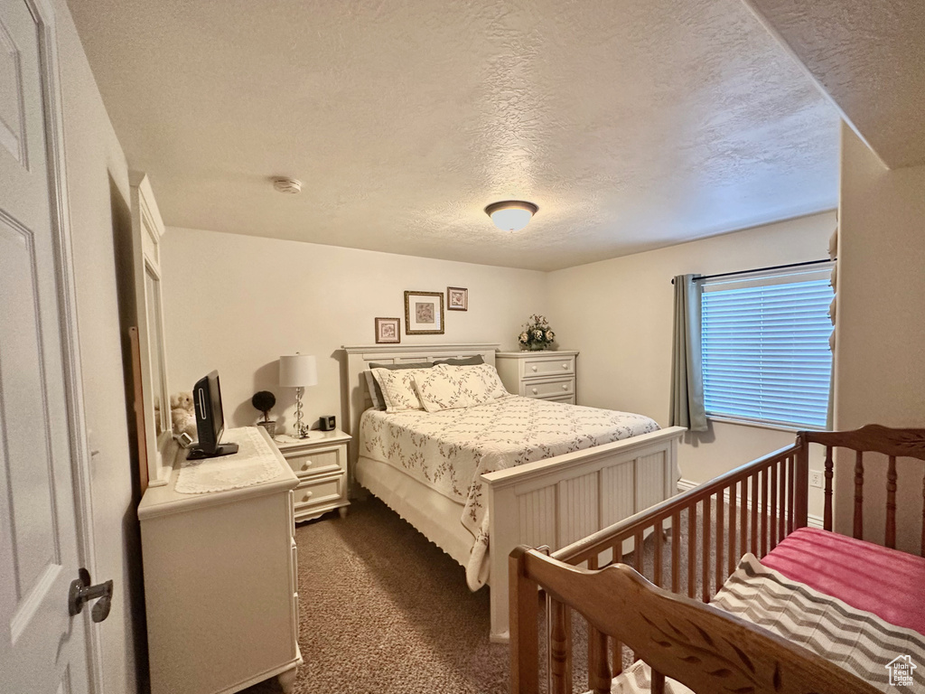Bedroom with dark carpet and a textured ceiling