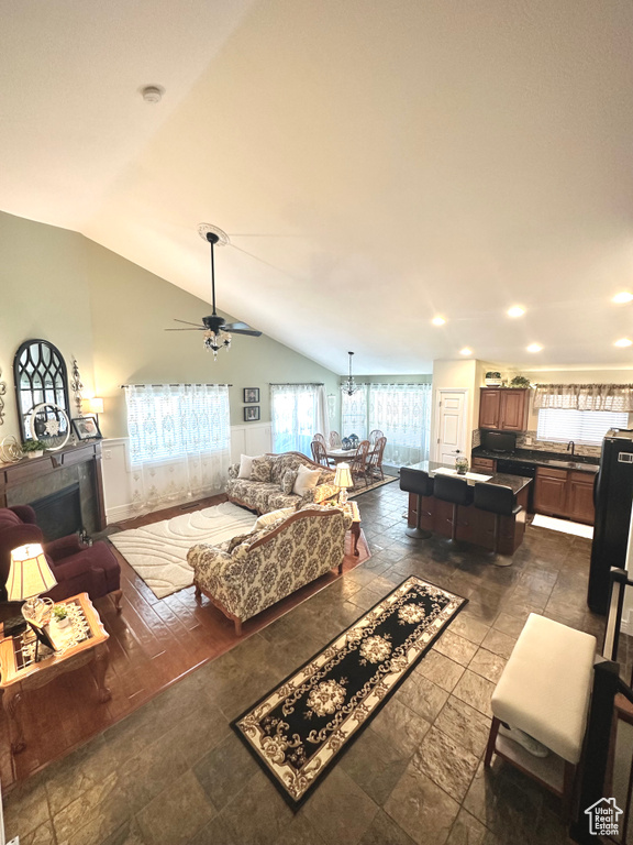Living area with lofted ceiling, stone tile floors, recessed lighting, and a ceiling fan