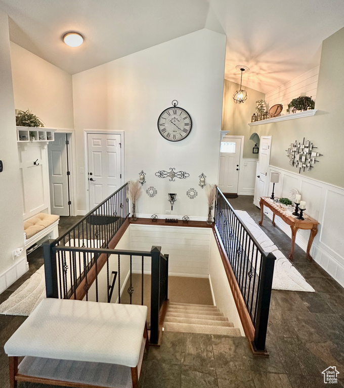 Stairway with high vaulted ceiling, wainscoting, and a decorative wall