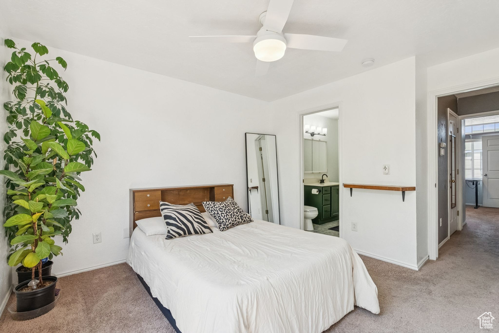 Carpeted bedroom featuring ensuite bath and a ceiling fan