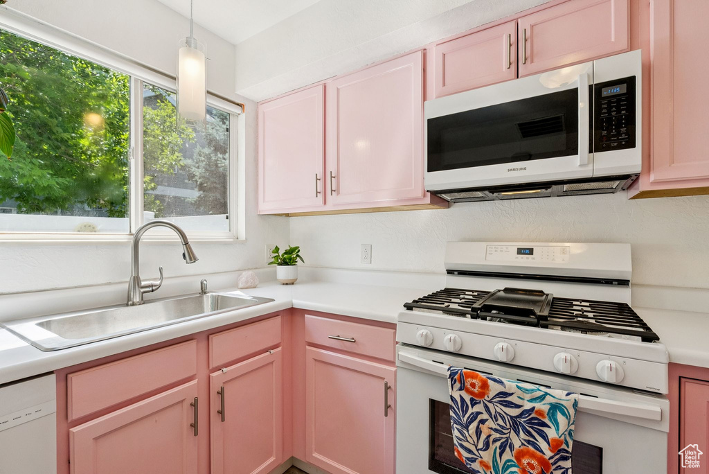 Kitchen featuring white appliances, light countertops, and decorative light fixtures