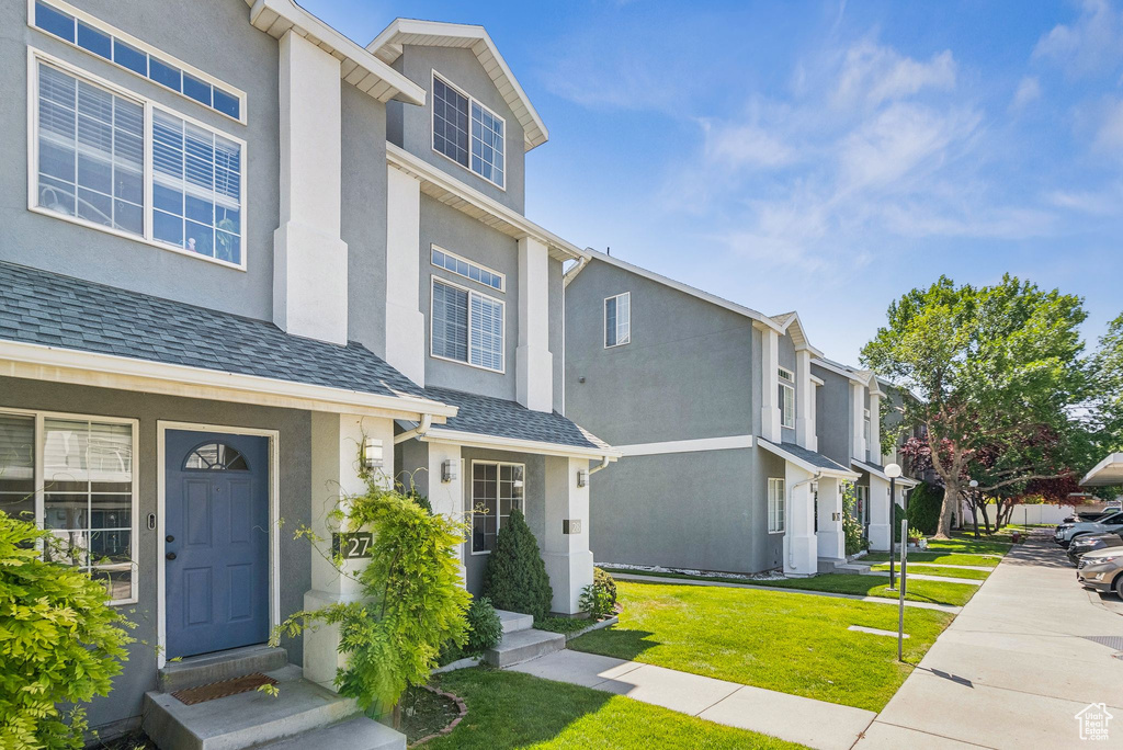 View of front facade featuring stucco siding, a front yard, and a residential view