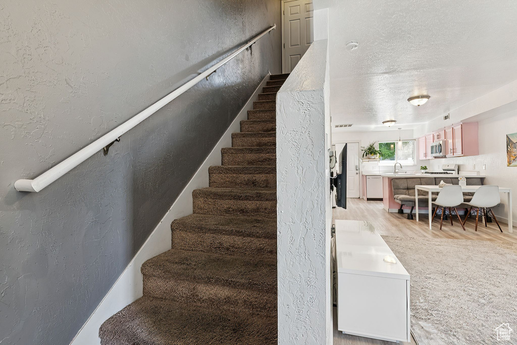 Stairs with wood finished floors and a textured wall