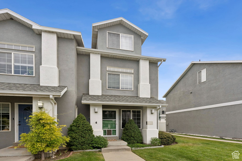 View of front facade featuring stucco siding and a front yard