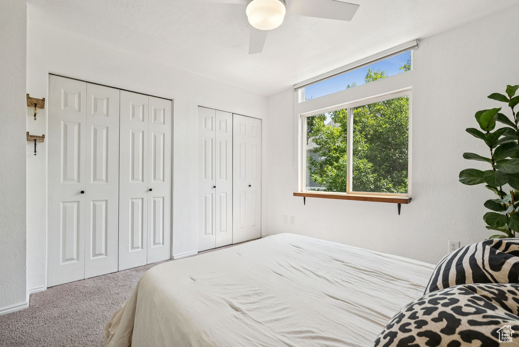 Carpeted bedroom featuring two closets and ceiling fan