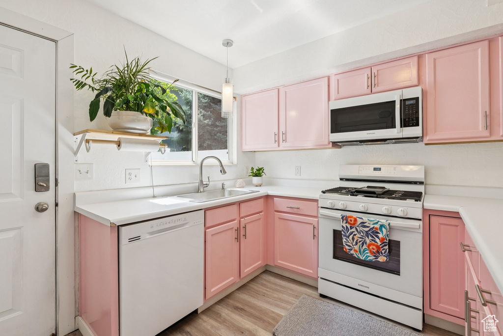 Kitchen featuring white appliances, light wood-style floors, light countertops, and hanging light fixtures