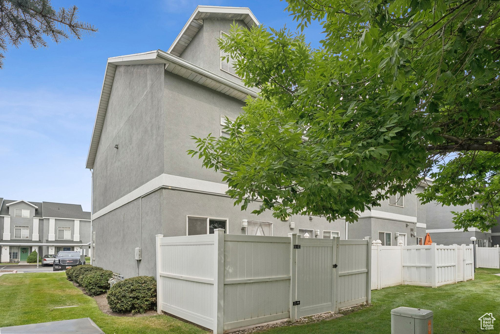 View of side of home with stucco siding and a gate