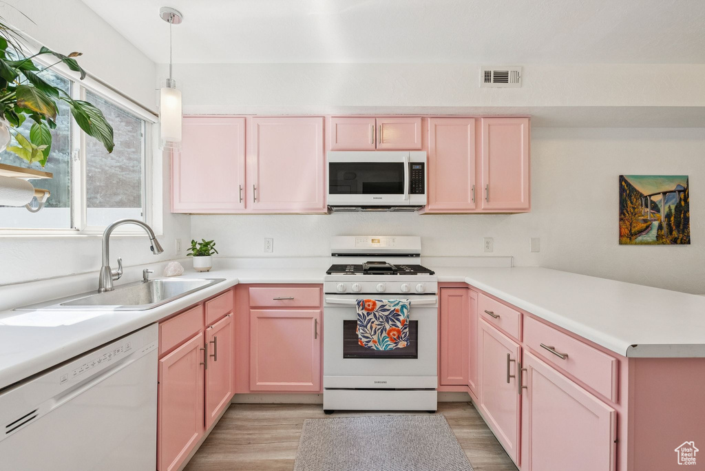 Kitchen featuring white appliances, a peninsula, light wood finished floors, and light countertops