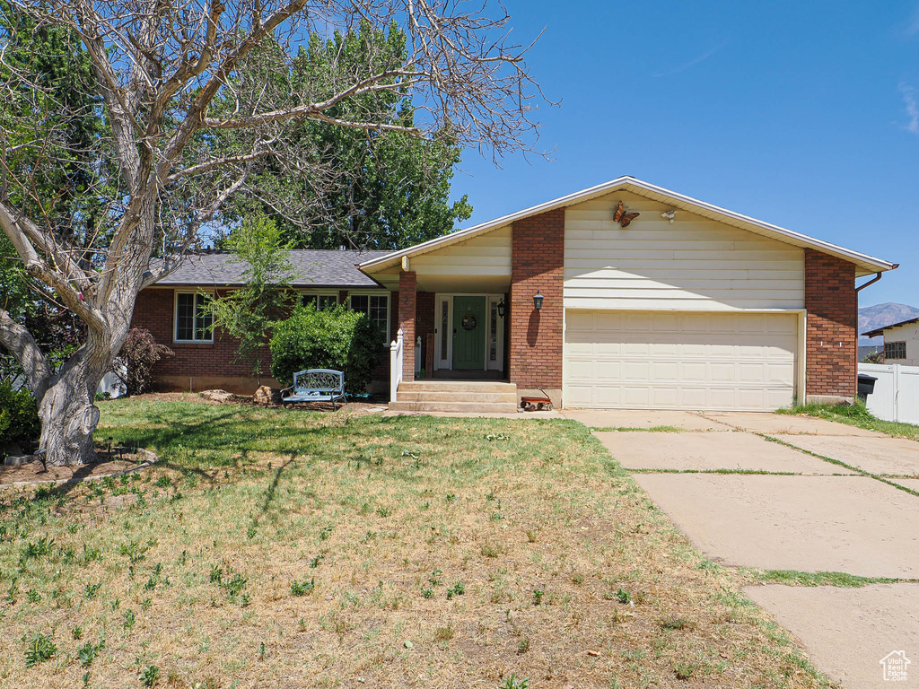 Ranch-style home featuring a garage, brick siding, concrete driveway, and a front lawn