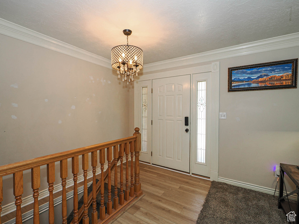 Entryway featuring a chandelier, light wood-style floors, and crown molding