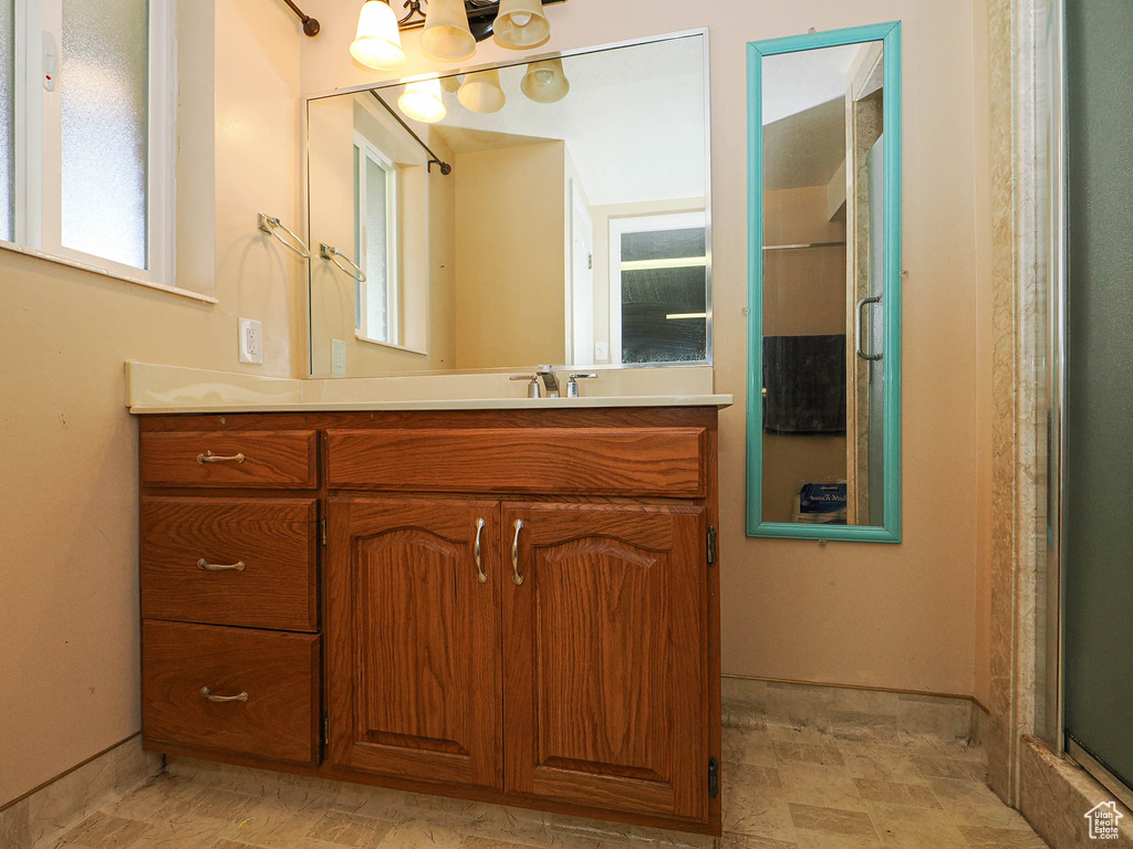 Bathroom with vanity, a chandelier, and a shower with shower door